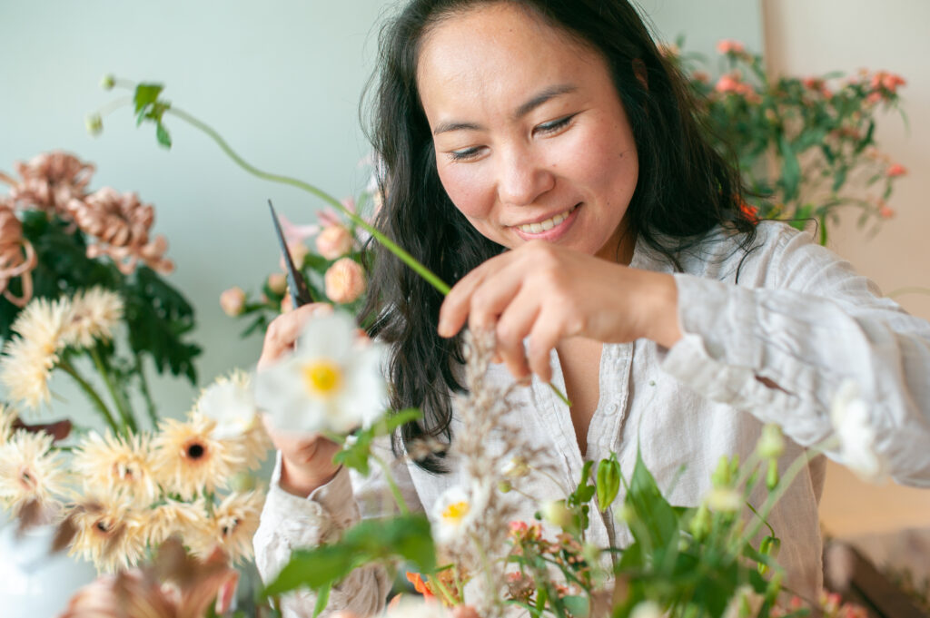 Floral designer maakt boeket en glimlacht vrolijk.